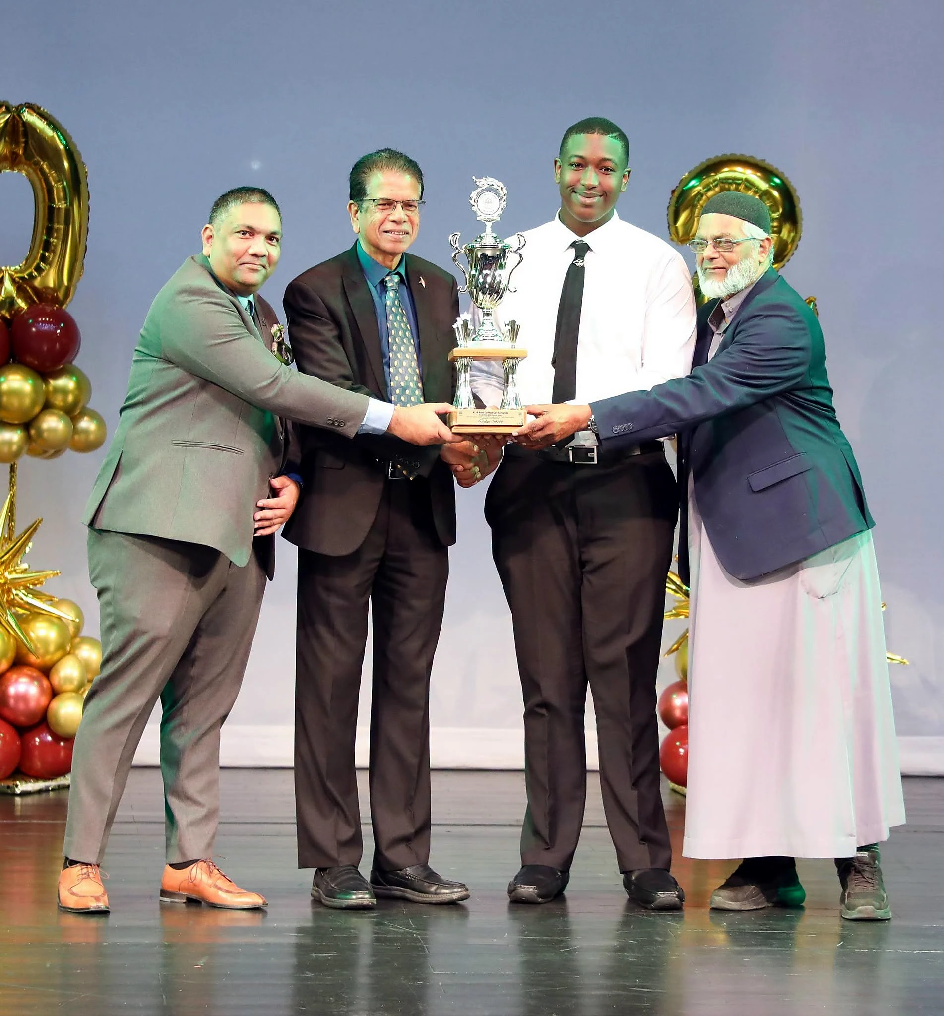 Award recipient holding a trophy with school and association representatives